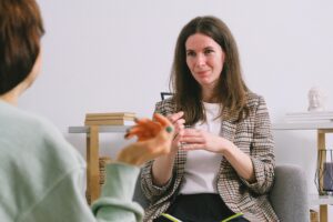 A therapist conducts a counseling session, engaging with a patient in a calm and supportive indoor setting.